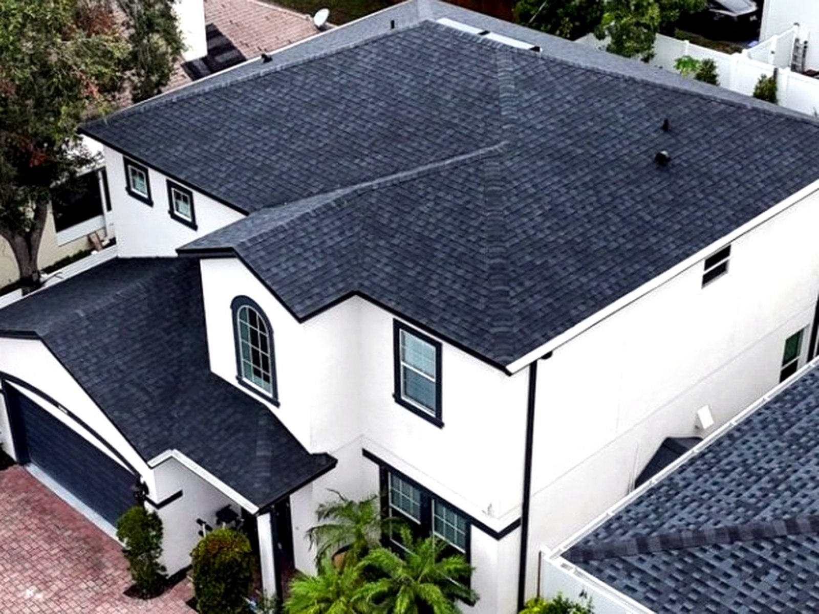 Completed dark charcoal architectural shingle roof on a two-story stucco home