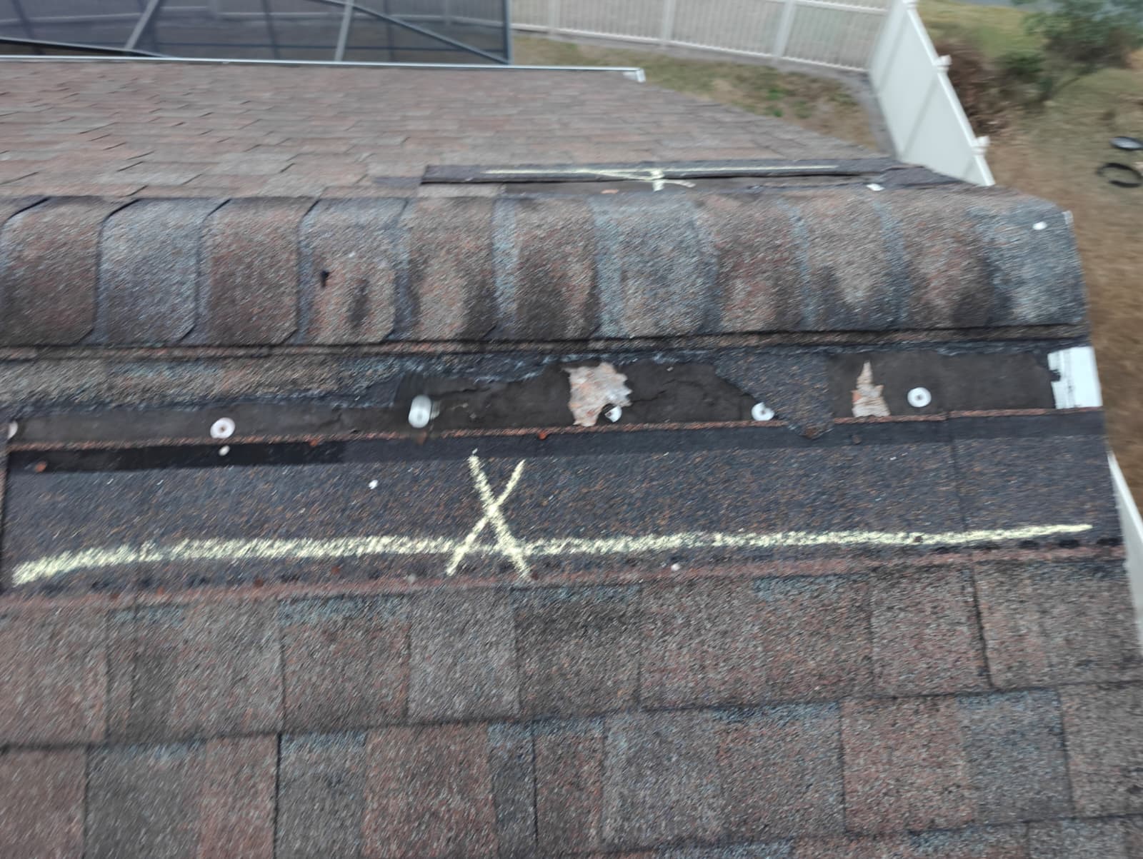 Exposed ridge line with displaced cap shingles after a storm