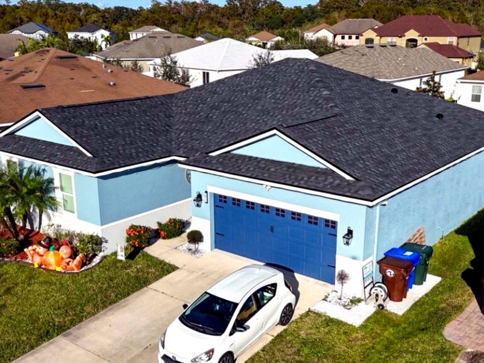 Deep black shingle roof on a coastal-blue two-story home