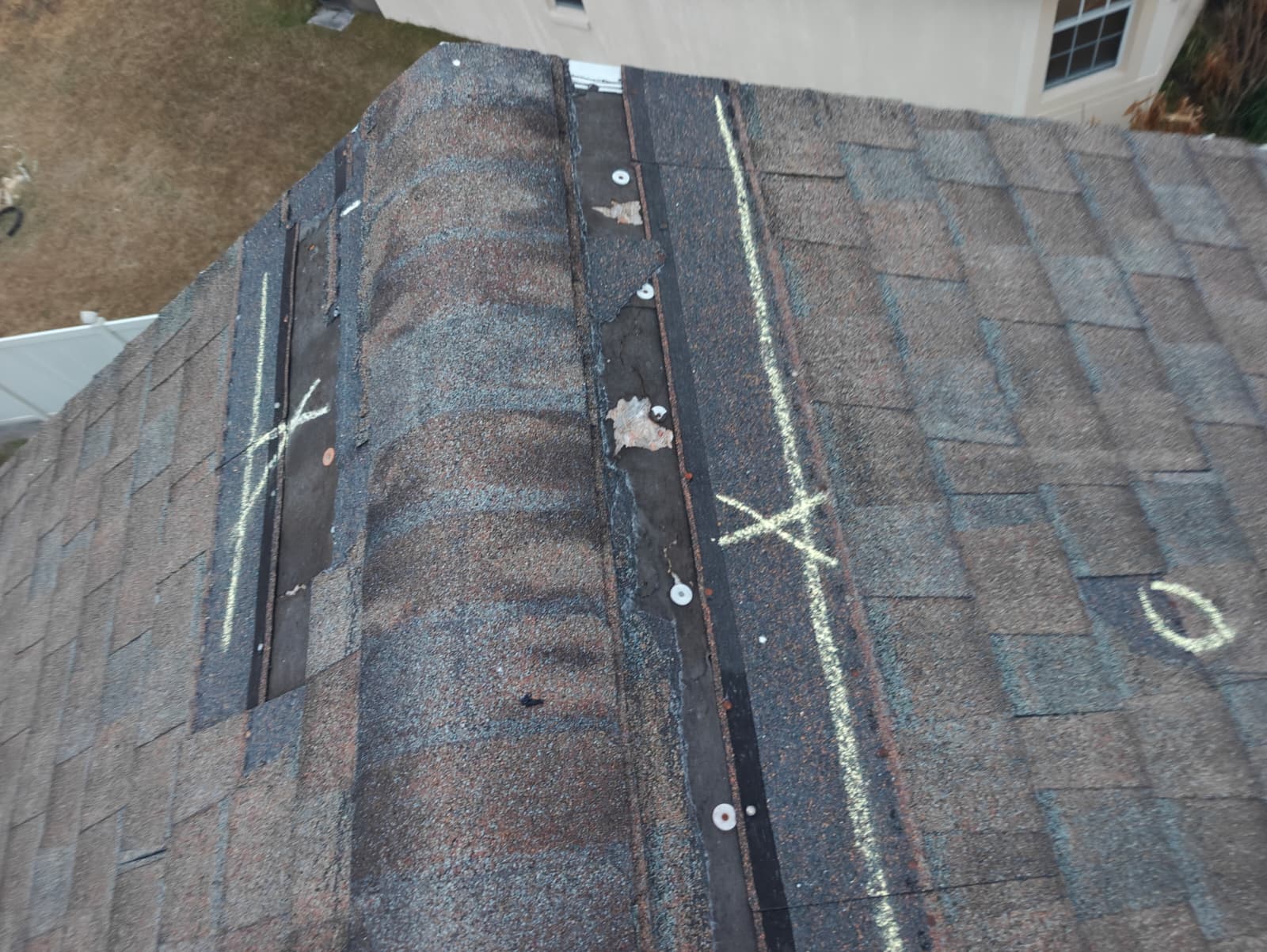 Ridge vent area with storm-lifted shingles marked during inspection